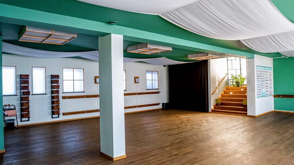 Rum som har skön atmosfär med mörkt trägolv, vita väggar och grönt tak